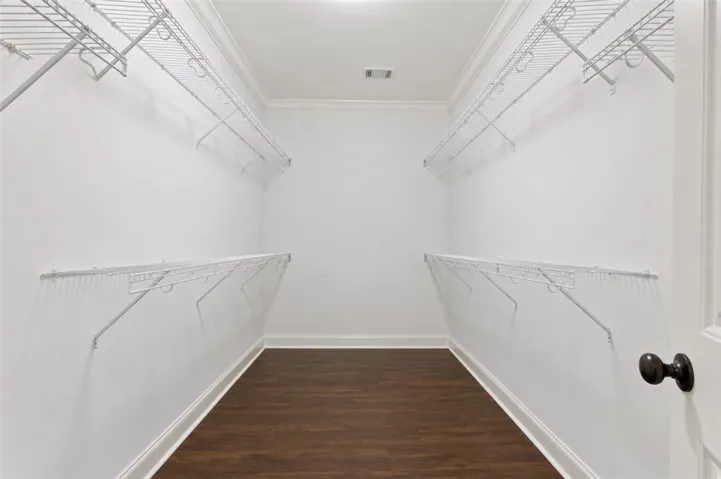 Walk-in closet offering ample storage with durable wire shelving and dark wood-look flooring.