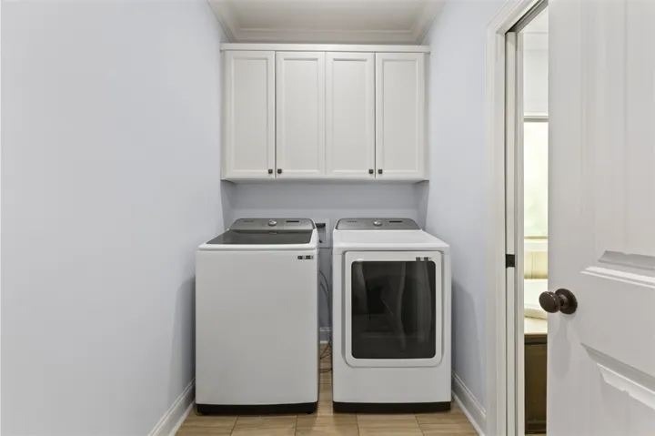 Functional laundry space featuring modern appliances and convenient overhead cabinetry.