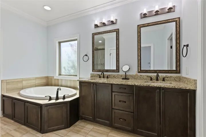 Luxurious bathing retreat boasts a deep soaking tub and dual granite vanities for ultimate relaxation.