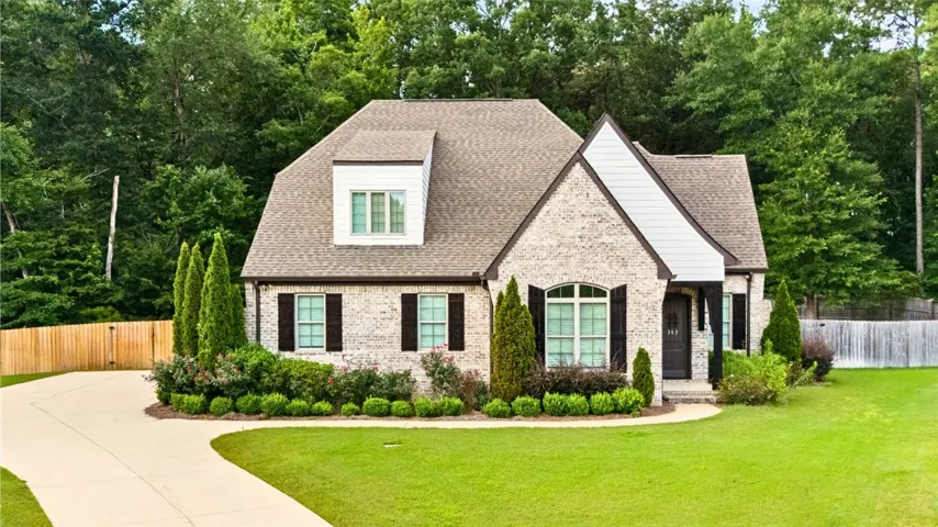 A graceful residence with a light brick facade and dark shutters offers superb curb appeal.