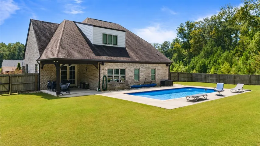 A spacious backyard with an inviting pool and expansive green lawn, perfect for outdoor enjoyment.