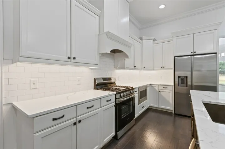 White cabinetry and subway tile backsplash elevate this modern kitchen with rich hardwood flooring.