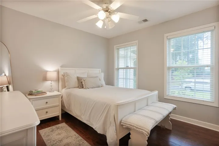 Hardwood floors and bright windows illuminate this comfortable bedroom space.
