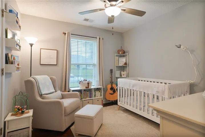 A well-lit nursery features a window and a ceiling fan, providing comfort and natural illumination.
