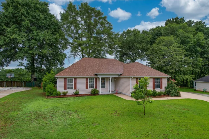 A well-maintained single-story residence with a neatly manicured lawn, framed by mature trees.