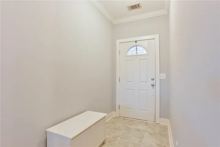 A welcoming entryway with tiled flooring and a classic door beckons guests into the residence.