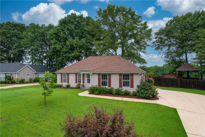 A well-maintained facade with red shutters and verdant landscaping frames this inviting residence.