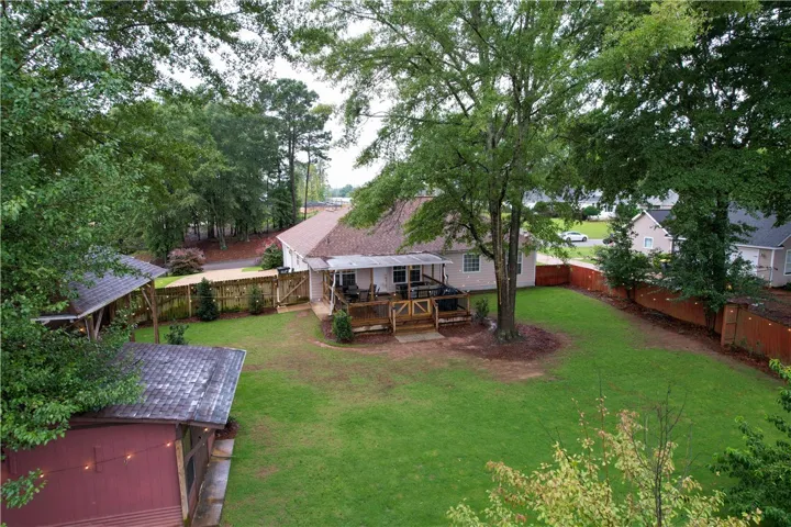 A spacious yard with mature trees and a fenced boundary complements the inviting back deck, perfect for outdoor relaxation.