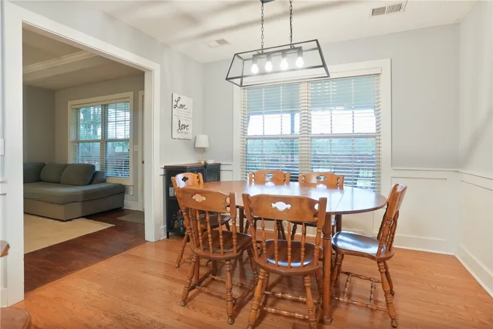 Hardwood floors and a linear chandelier highlight this bright dining area.
