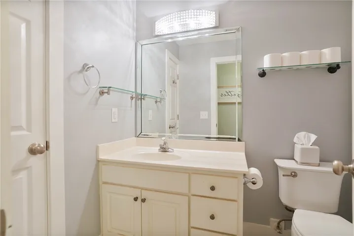 A well-lit bathroom features a spacious vanity and a large mirror with elegant lighting.