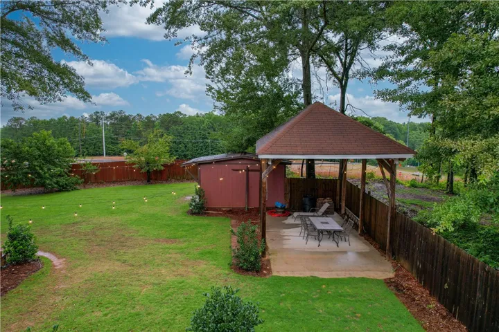 A spacious yard features a covered patio perfect for outdoor entertaining, alongside a practical storage shed.