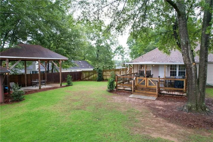 A spacious yard boasts a wooden deck and covered patio, perfect for outdoor relaxation and entertaining.