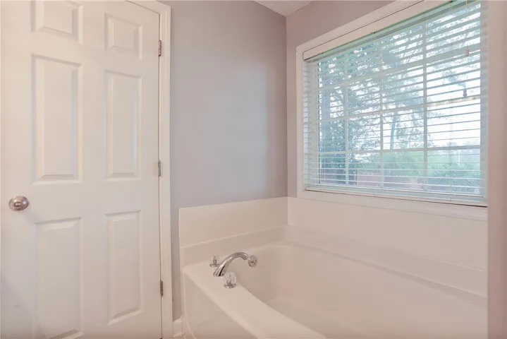 A spacious tub awaits, offering a tranquil retreat with a window view to nature's greenery.