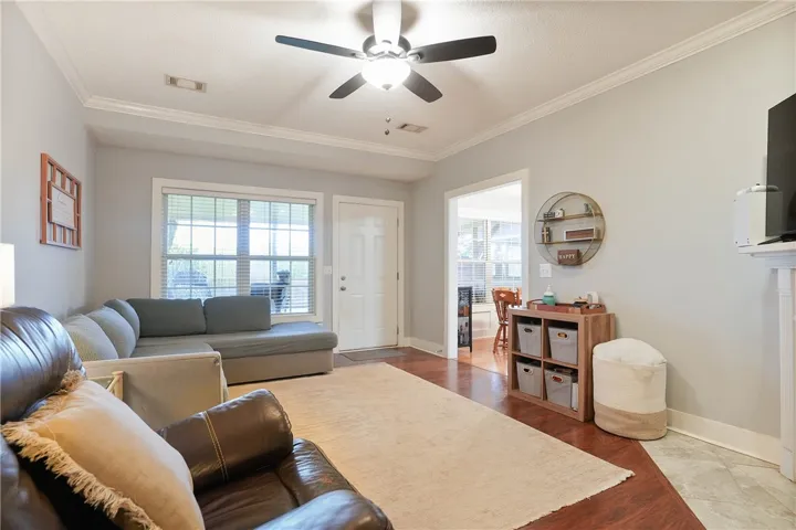 A comfortable living space boasts a ceiling fan, a large window, and rich wood flooring.