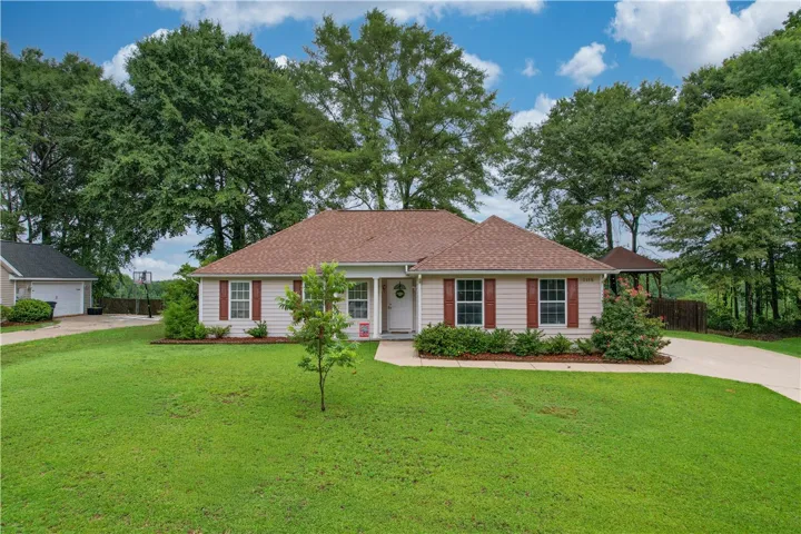 A classic ranch home features a covered entry, tidy landscaping, and a broad lawn.