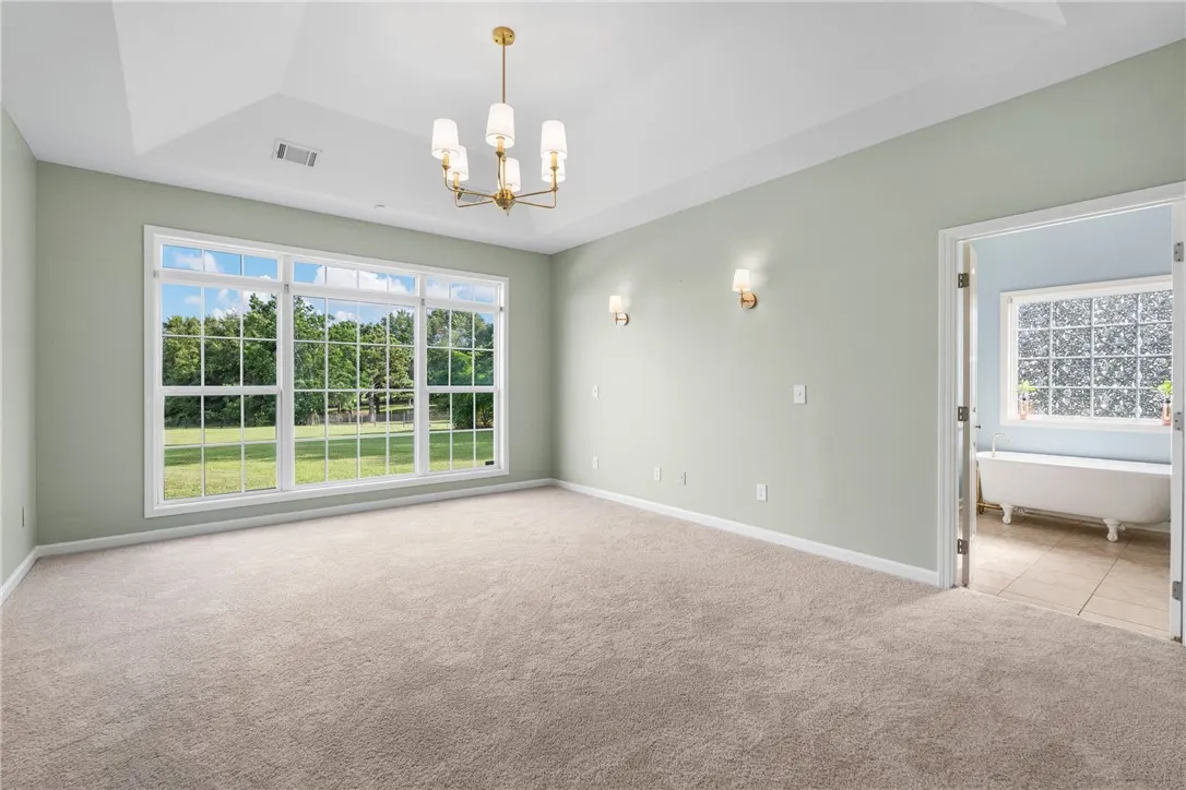 A spacious chamber with a vaulted ceiling and a wide window offers verdant outdoor views.