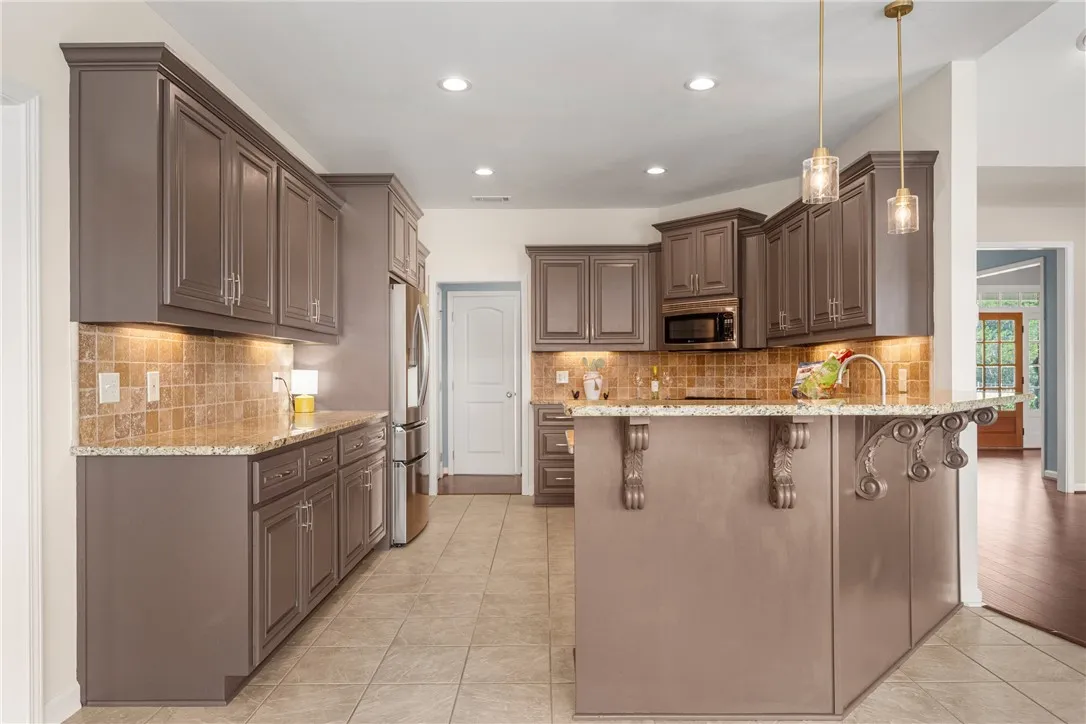 An inviting culinary space offers abundant cabinetry, stone counters, and practical island with breakfast bar.