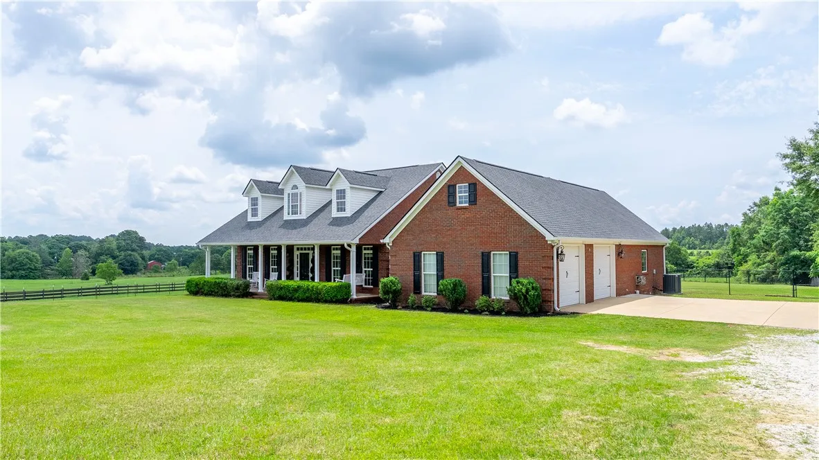 A classic brick exterior with a welcoming porch and abundant green space offers serene country living.