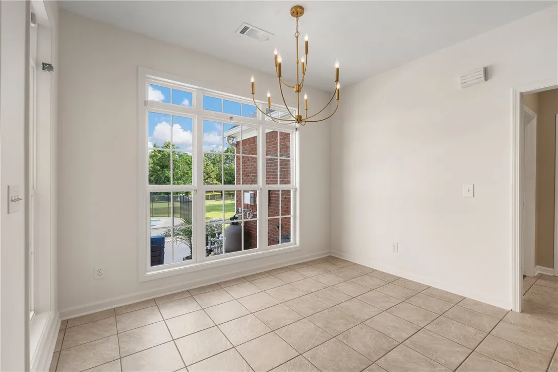 A refined dining space with ample natural light, tile flooring, and a contemporary brass chandelier.