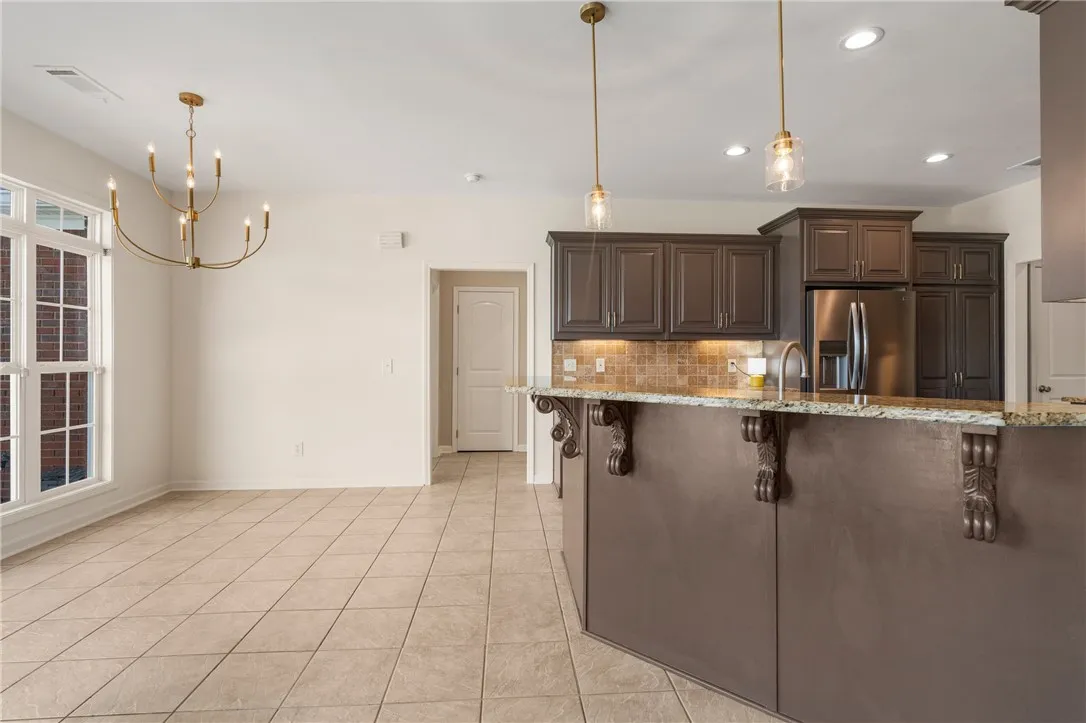 A well-appointed kitchen island with carved corbels anchors the open concept living space, bathed in natural light from broad windows.