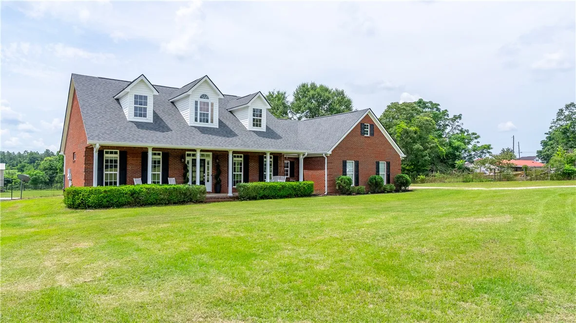 A classic brick-front residence with a deep, welcoming porch overlooks a vast green lawn.