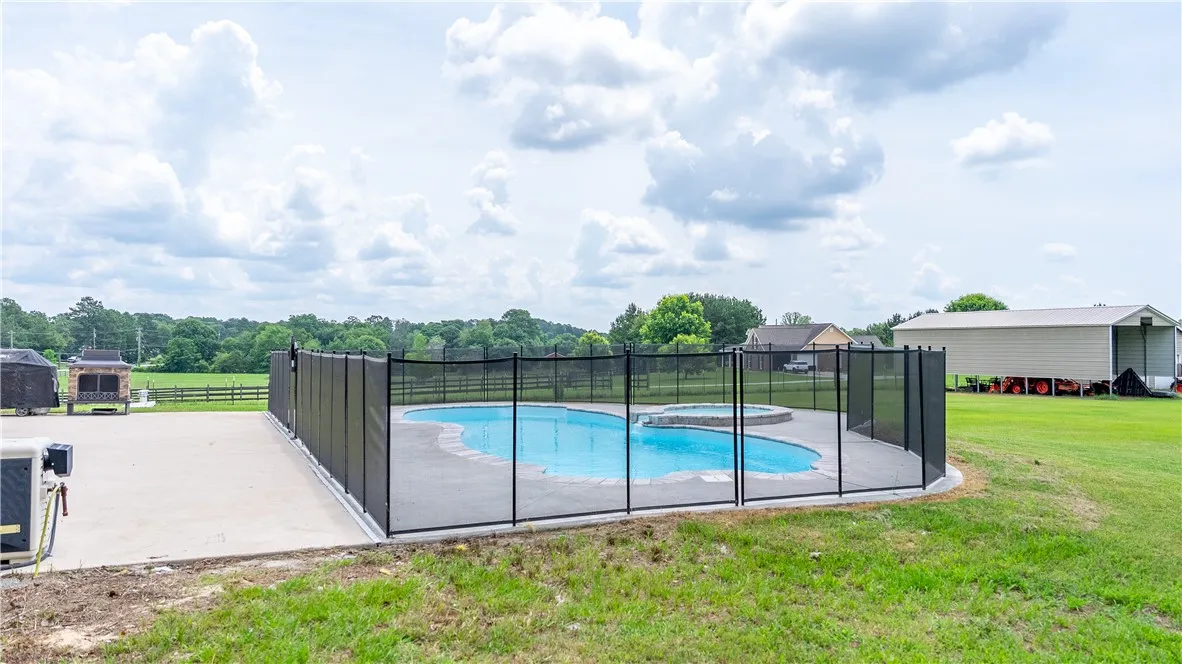 A private, in-ground swimming pool with an attached spa, enclosed by a safety fence.
