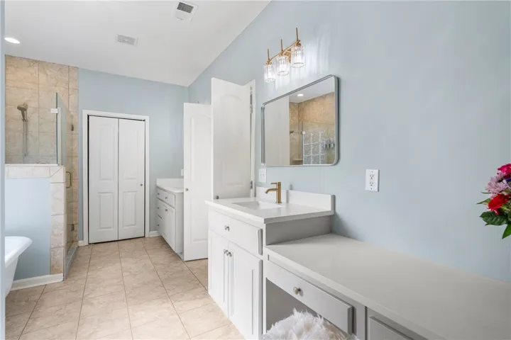 A pristine bathroom featuring a double vanity, a modern walk-in shower, and ample storage.