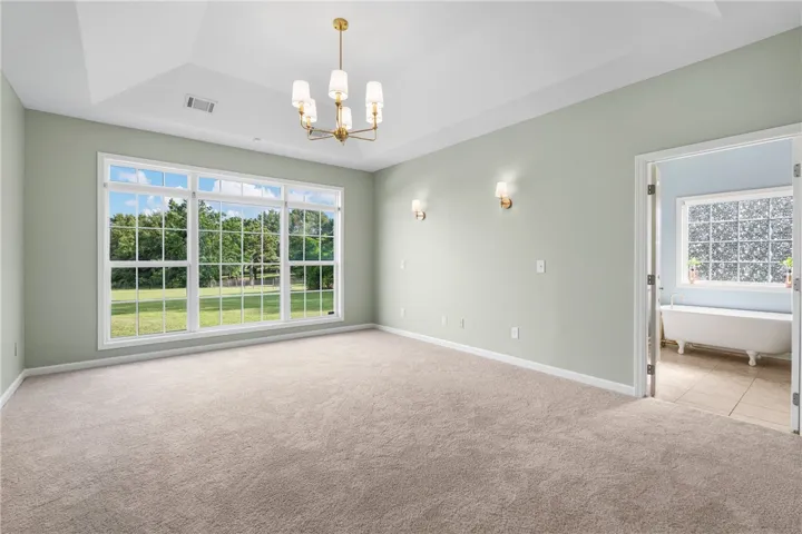 A spacious chamber with a vaulted ceiling and a wide window offers verdant outdoor views.