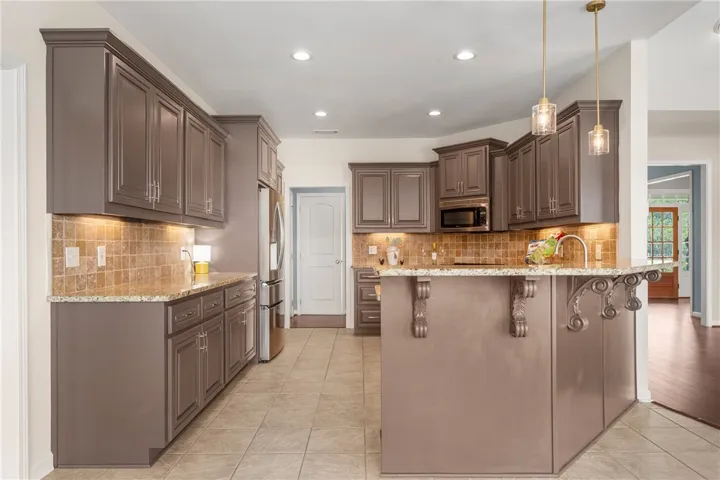 An inviting culinary space offers abundant cabinetry, stone counters, and practical island with breakfast bar.