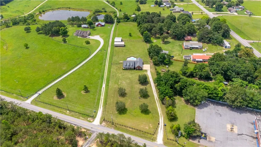 An aerial perspective reveals a serene countryside estate with a private pond and winding driveways.