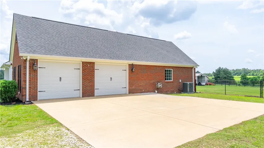 A classic brick garage with dual doors and an ample concrete driveway, nestled beside a green expanse.
