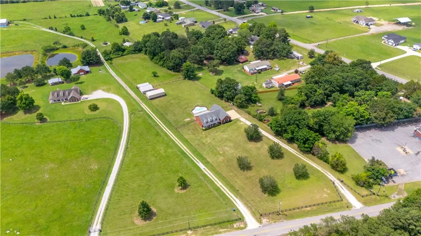 An aerial perspective showcases a secluded property with a private pool and winding driveways, nestled within lush green​​‌​​​​‌​​‌‌​‌‌​​​‌‌​‌​‌​‌​​​‌​​ fields.