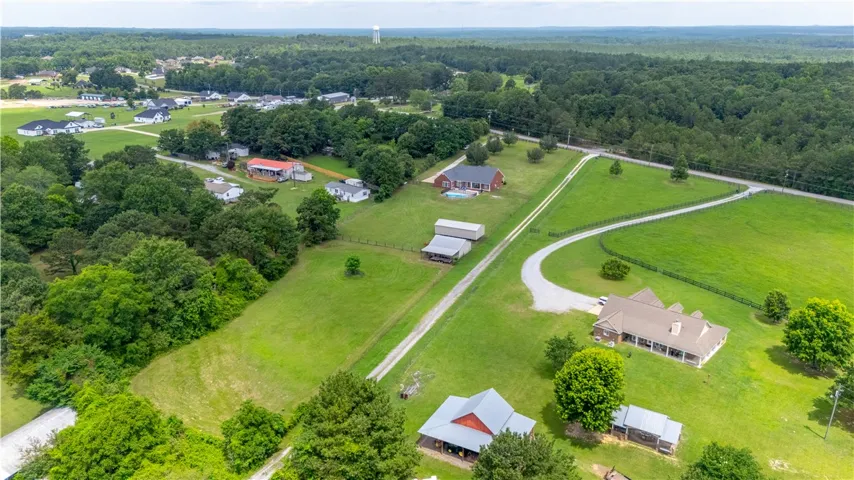 An aerial perspective reveals a vast estate with multiple residences amidst rolling green acreage.