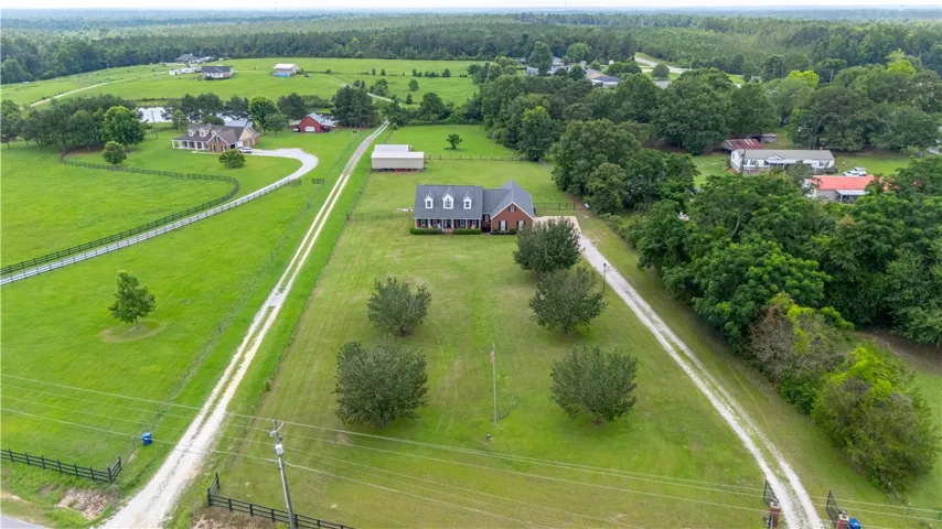 Rolling green acreage with a winding driveway leads to a classic brick home.