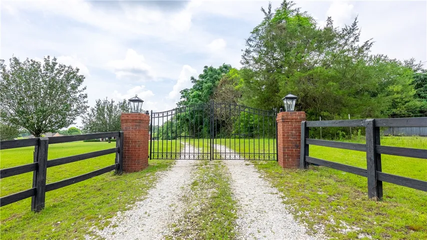 A grand, gated entrance awaits, flanked by brick pillars and a well-maintained fence.