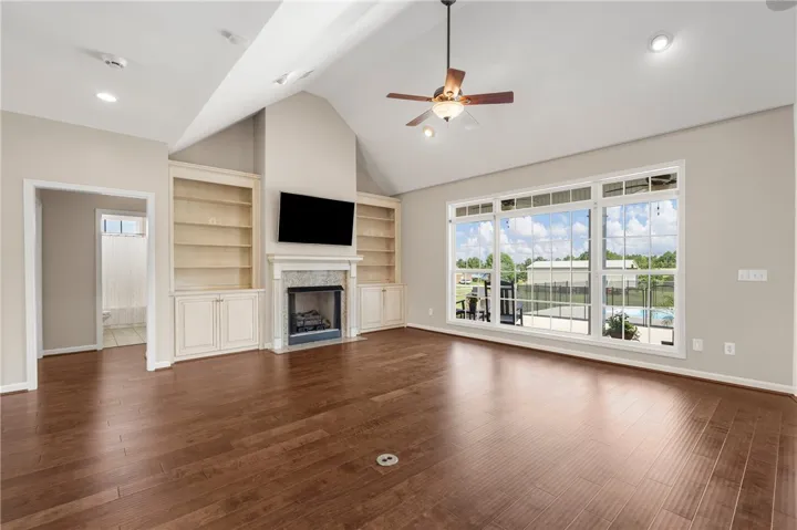 A spacious living room with vaulted ceilings and a stunning fireplace provides serene pool views.