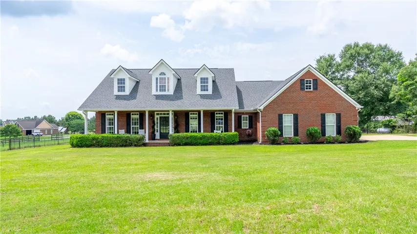 A classic brick-front home featuring a welcoming covered porch and meticulously maintained landscaping.