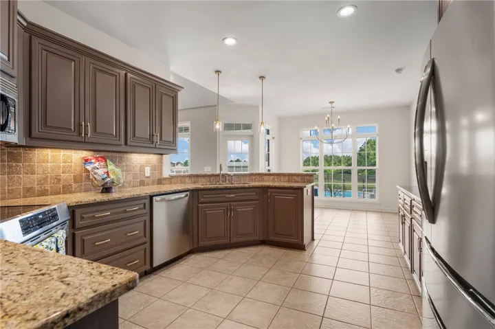 A well-lit kitchen with granite countertops and modern appliances seamlessly connects to an inviting outdoor space with a pool view.