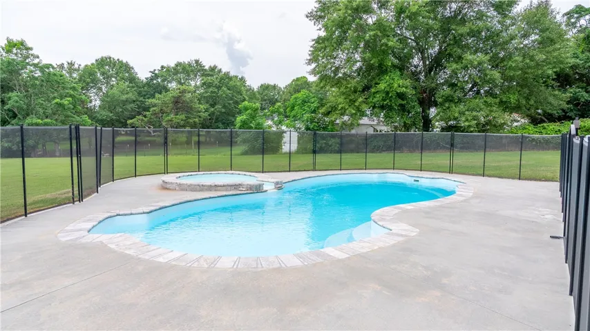 A fenced backyard retreat awaits, complete with a sparkling in-ground pool and integrated spa.