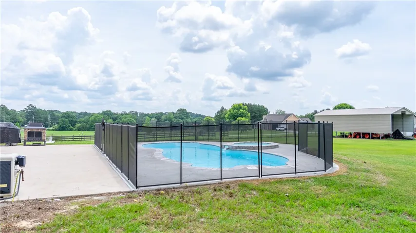 A private, in-ground swimming pool with an attached spa, enclosed by a safety fence.