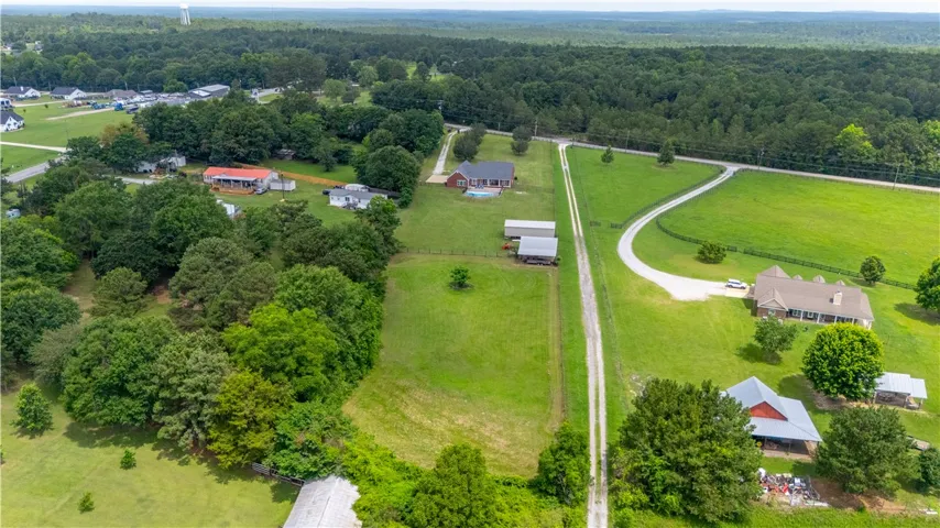 Sprawling estate with multiple residences and outbuildings set against a backdrop of mature trees.