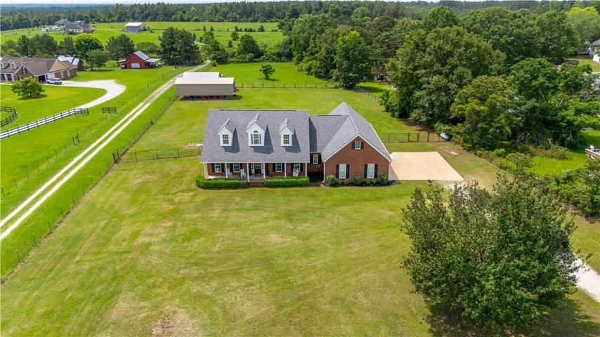 An inviting front porch welcomes you to this spacious brick residence amidst generous green acreage.