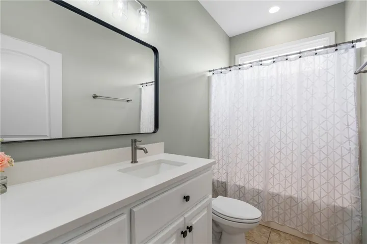 A pristine vanity with generous counter space, under-sink storage, and a modern rectangular mirror.
