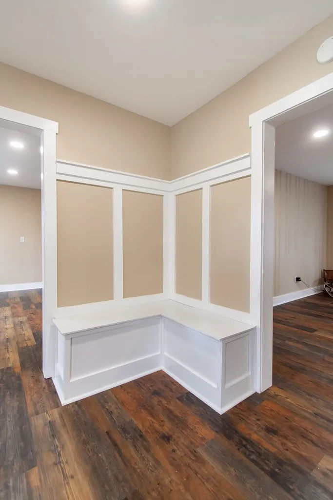 Built-in corner bench seating with crisp white wainscoting provides a welcoming touch in this inviting entry.