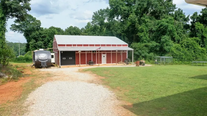 A spacious red barn with a covered porch offers ample outdoor storage, great entertaining area.