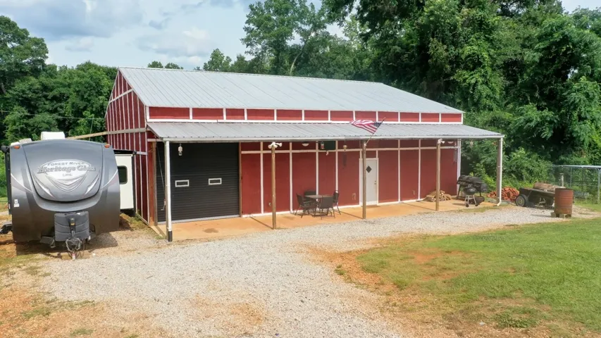 A spacious red barn structure with an extended porch offers ample outdoor living and utility space.