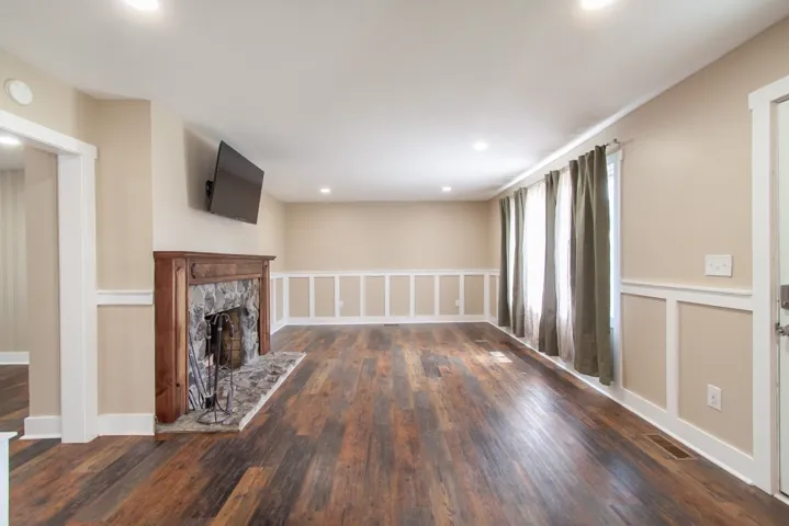 Spacious and boasts a charming stone fireplace with a decorative mantel.