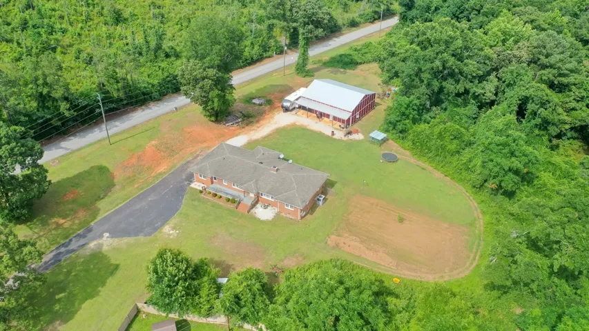Sprawling grounds embrace a classic brick residence alongside a sizable red barn and abundant green space.