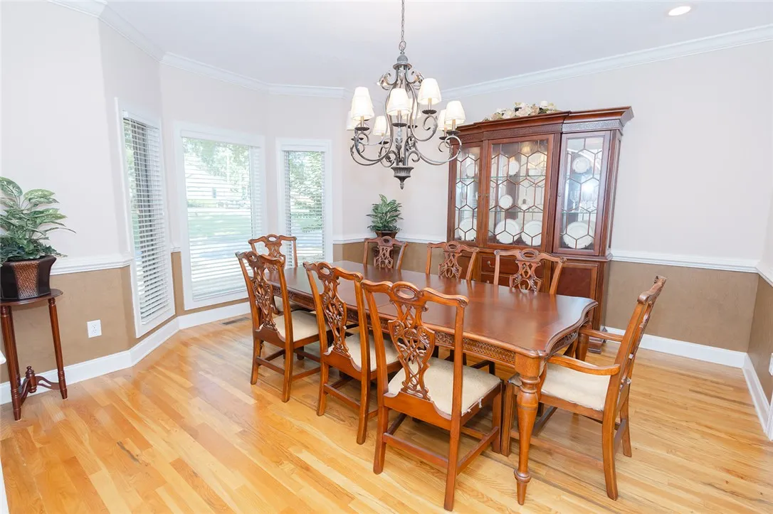 Hardwood floors and a detailed chandelier elevate this spacious formal dining area.