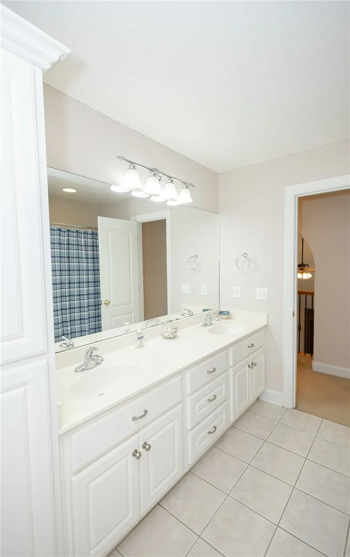 White cabinetry and tile flooring define this well-appointed double vanity bathroom.